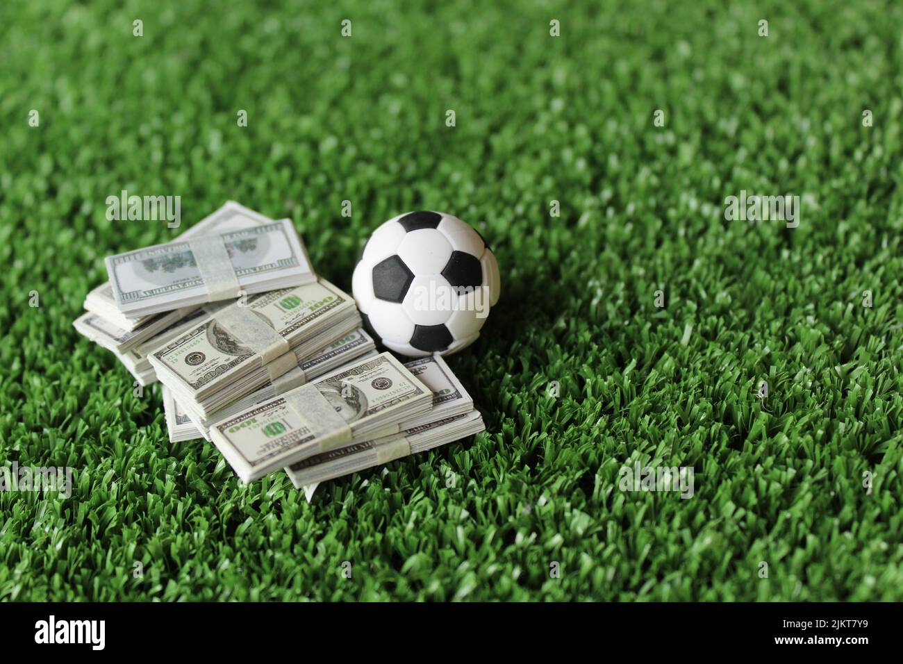 Selective focus image of soccer football and money on field. Sport betting and bribery concept Stock Photo