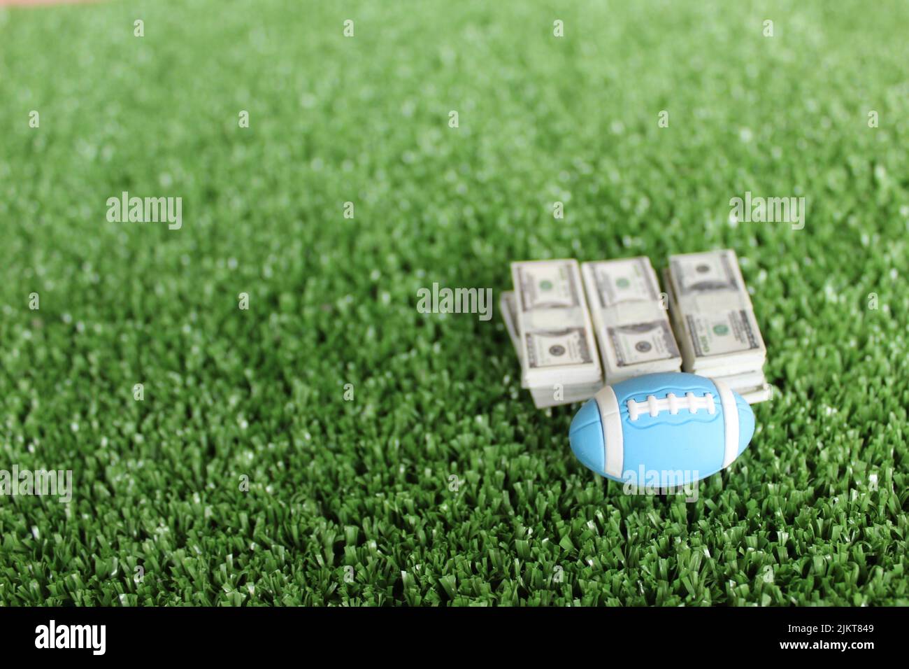 Selective focus image of rugby ball and money on field. Sport betting and bribery concept Stock Photo
