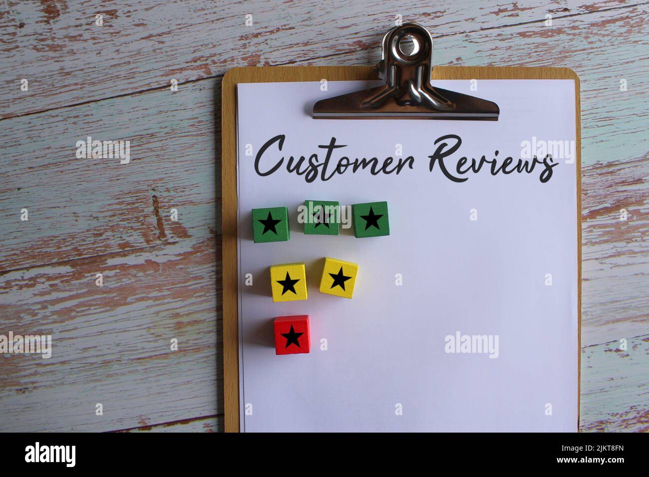 Paper clipboard with text Customer Reviews and wooden cube with star