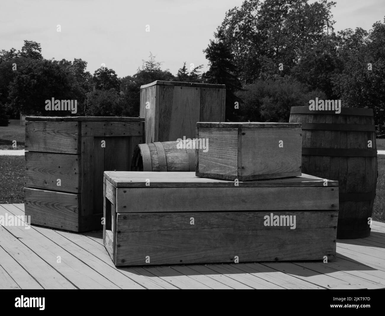 A grayscale view of wooden boxes and barrels in the rural area Stock Photo
