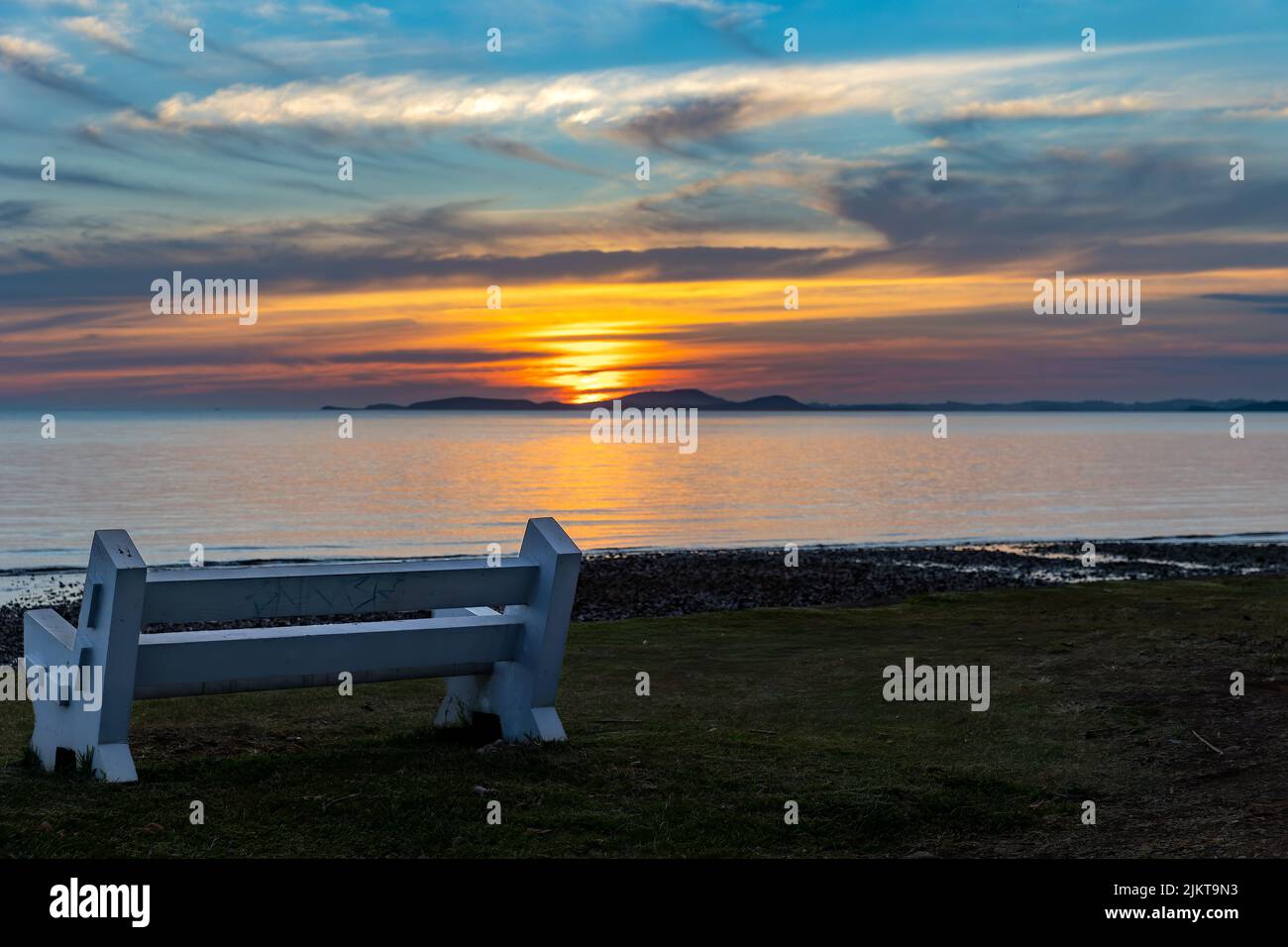 Reflection of sun at a bench with the offshore Sainte Marie island at sunset, view from Plum, New caledonia Stock Photo