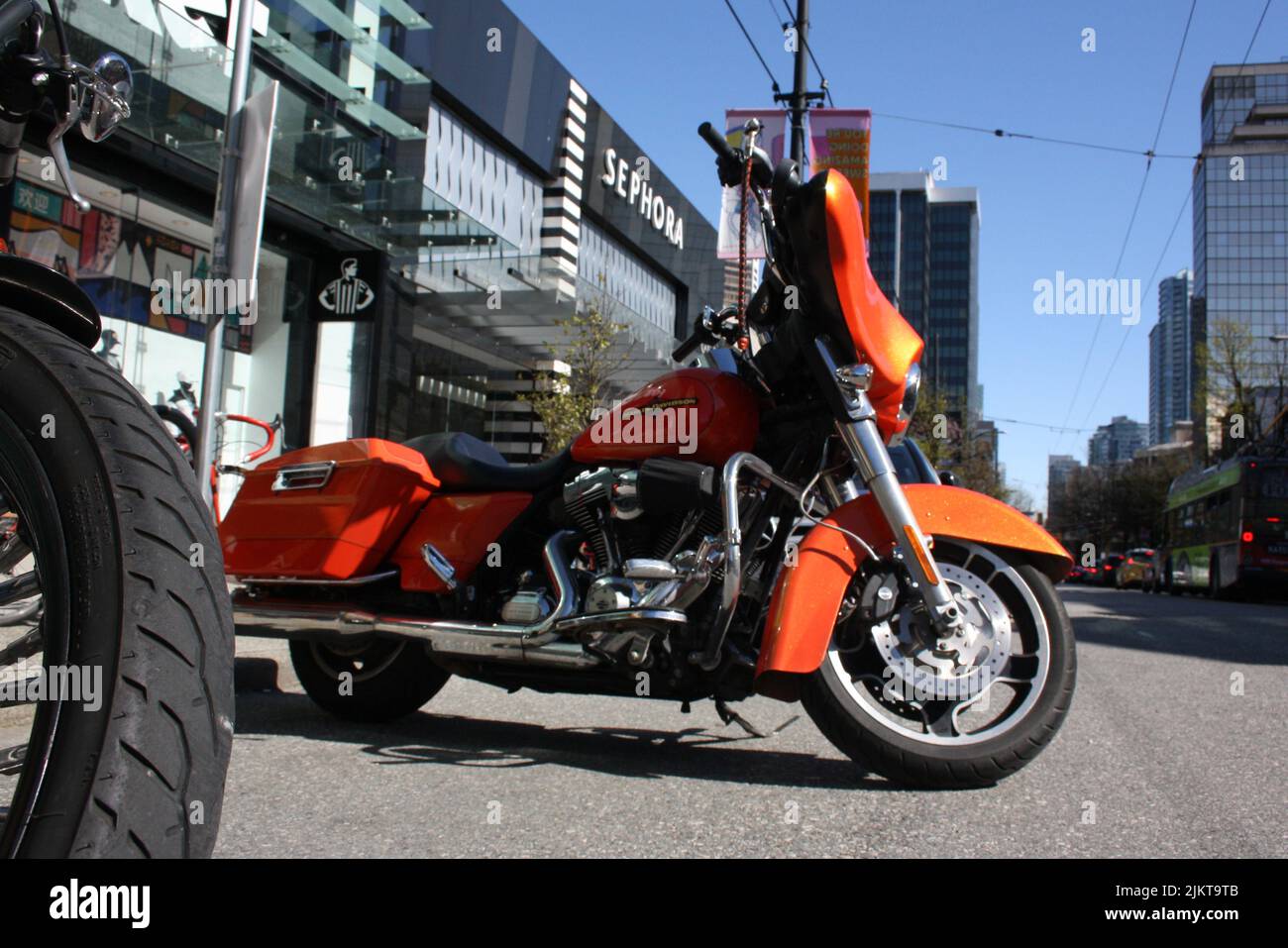 A orange Harley Davidsson mode motorcycle in the street of downtown Vancouver in Canada Stock Photo