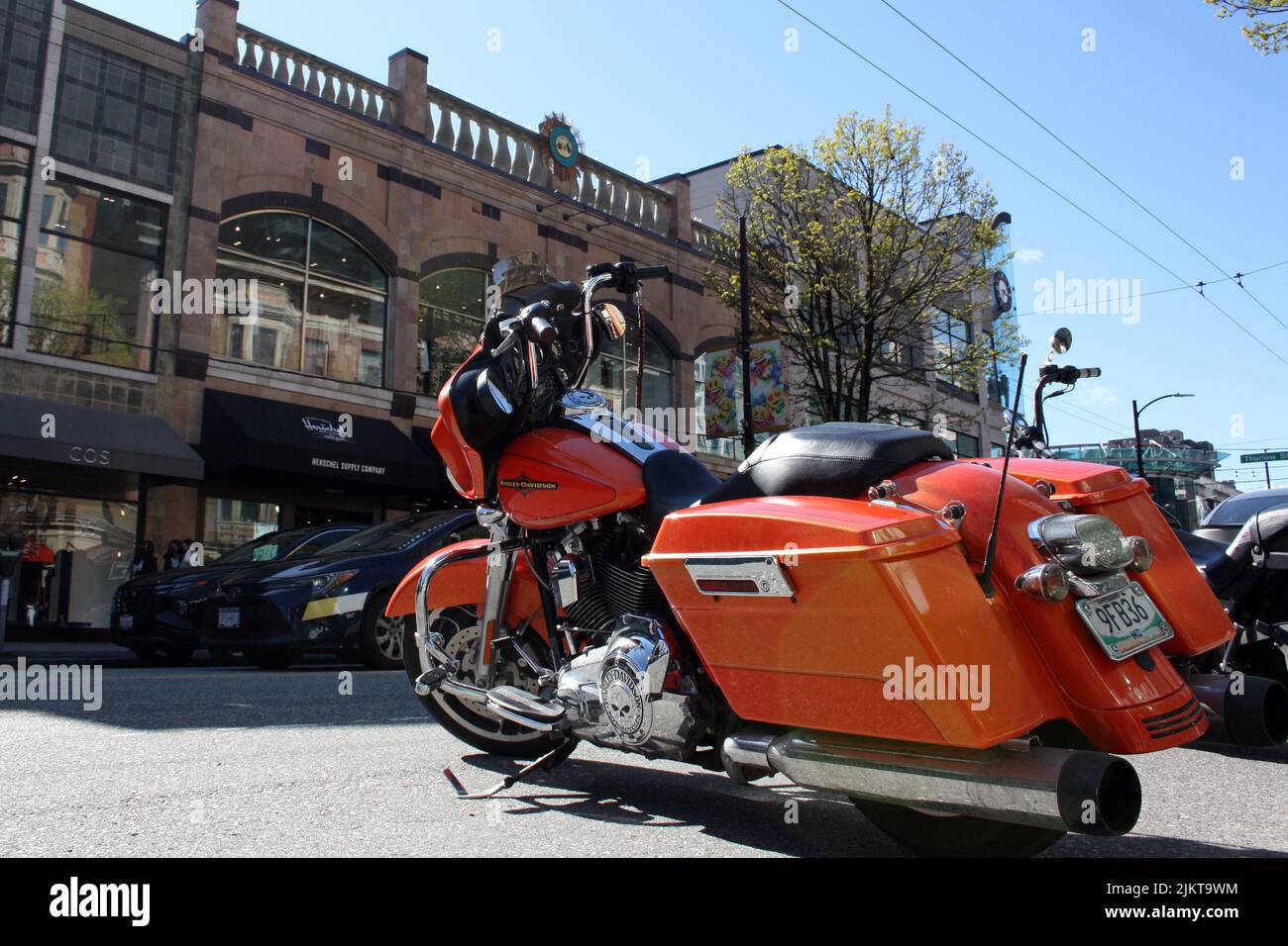 A orange Harley Davidsson motorcycle in the street of downtown Vancouver in Canada Stock Photo