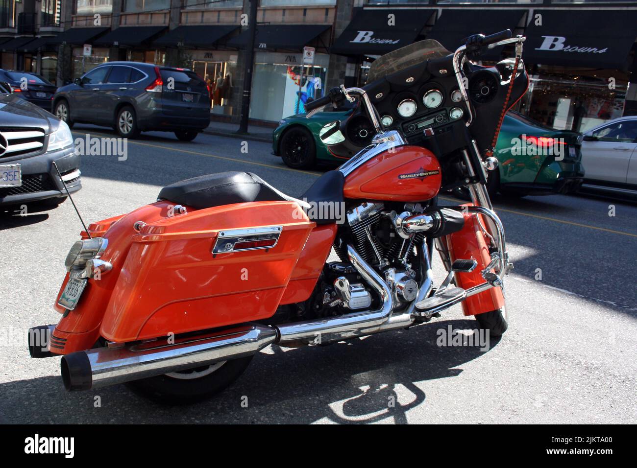 A orange Harley Davidsson motorcycle in the street of downtown Vancouver, British Columbia, Canada Stock Photo
