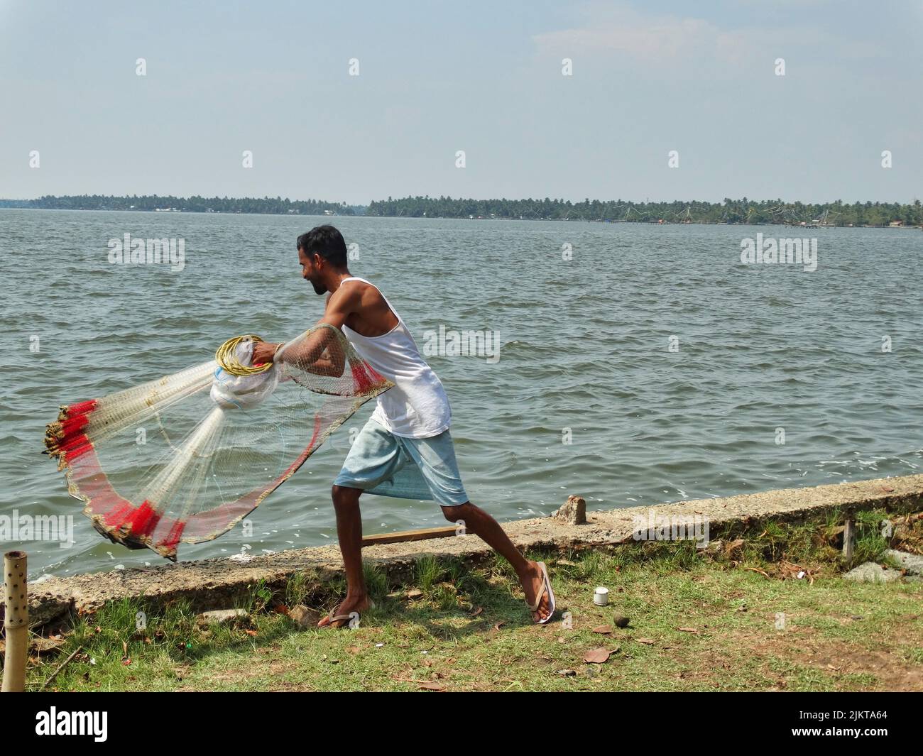 The photo shows an Indian fisherman in New Mangalore doing the traditional fishing with a net. Stock Photo