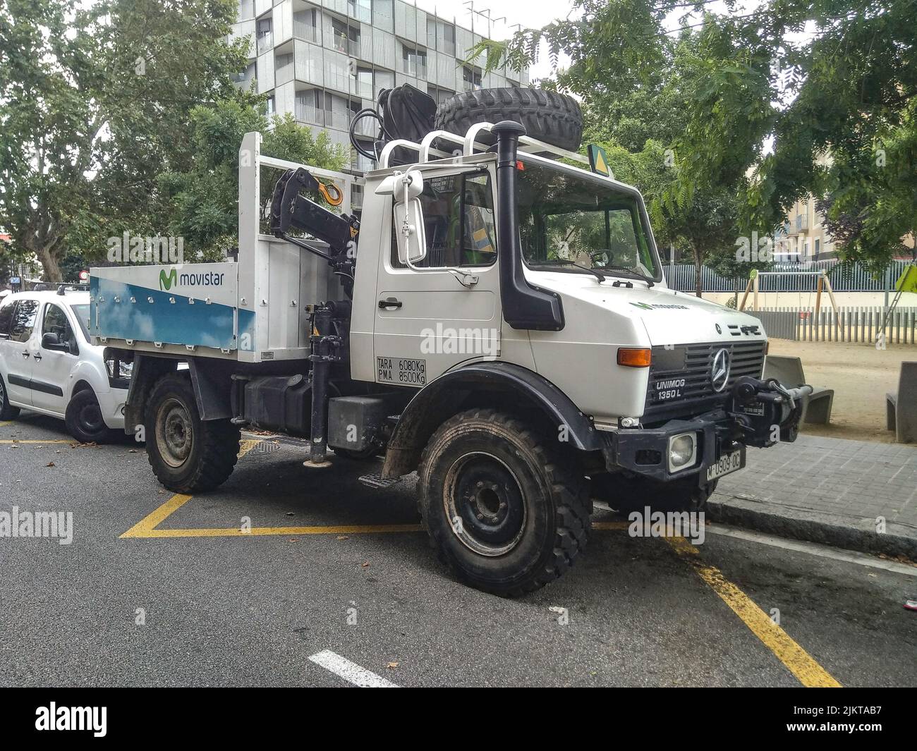 Big off road truck with crane parked in the city. The truck is color white Mercedes Benz Unimog of Movistar Telefonica company Stock Photo