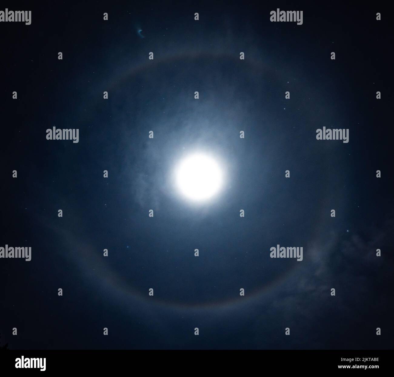A beautiful shot of the Moon shining in the sky with a halo circle at night Stock Photo