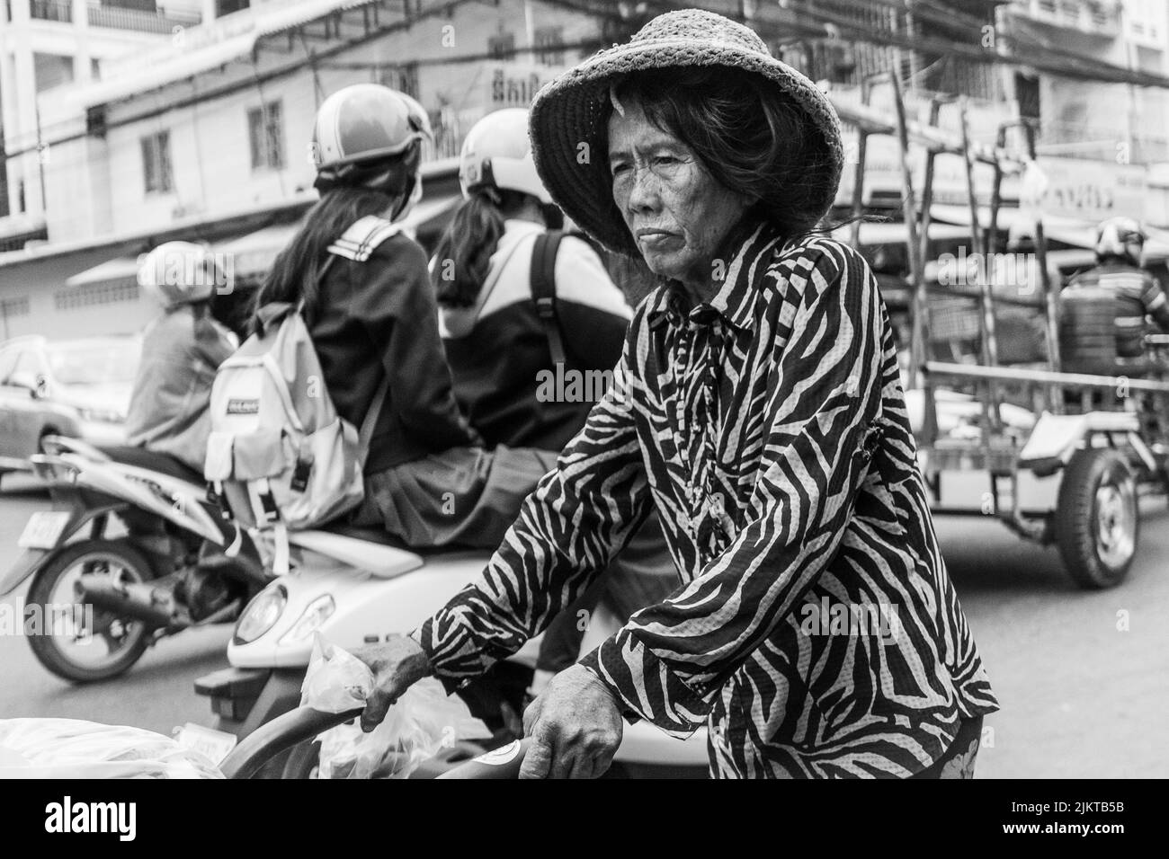 A grayscale shallow closeup shot of an old woman Vendor pulling a trolley in Phnom Penh, Cambodia Stock Photo