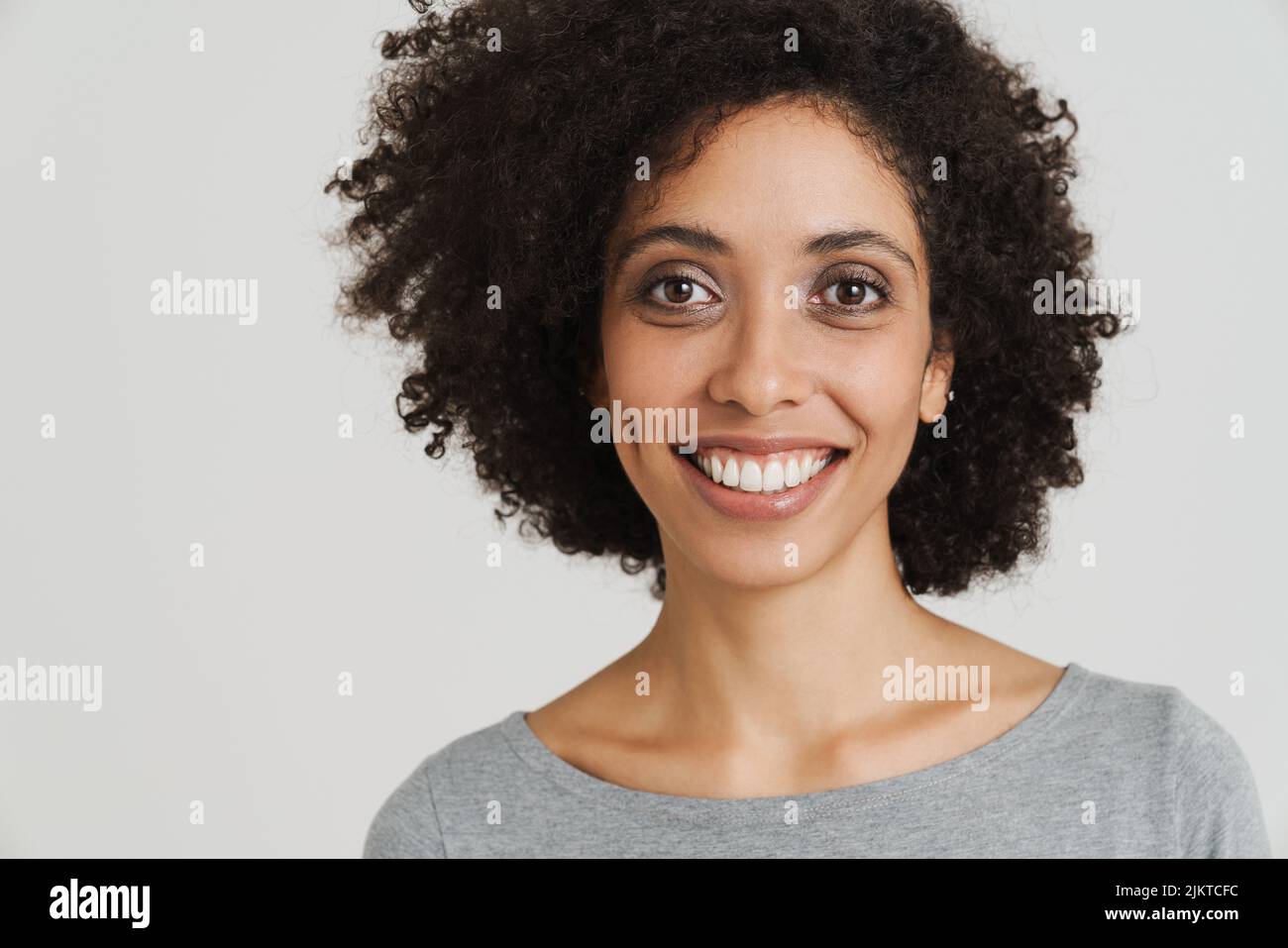 Young black woman with curly hair smiling and looking at camera ...