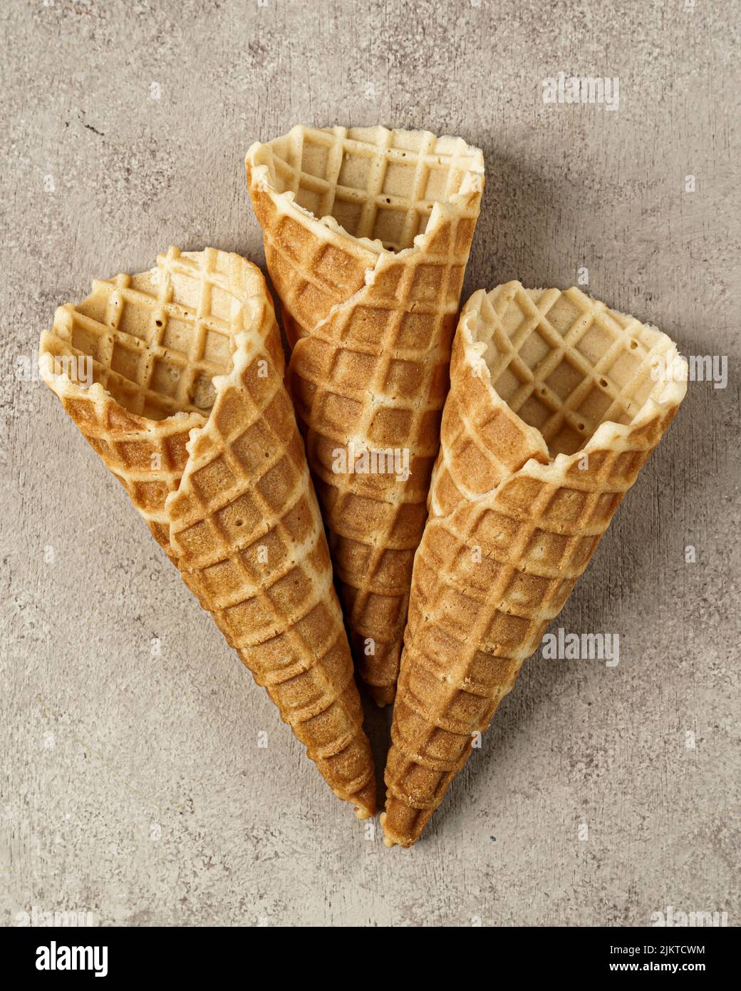 A vertical shot of three empty ice cream cones over brown background