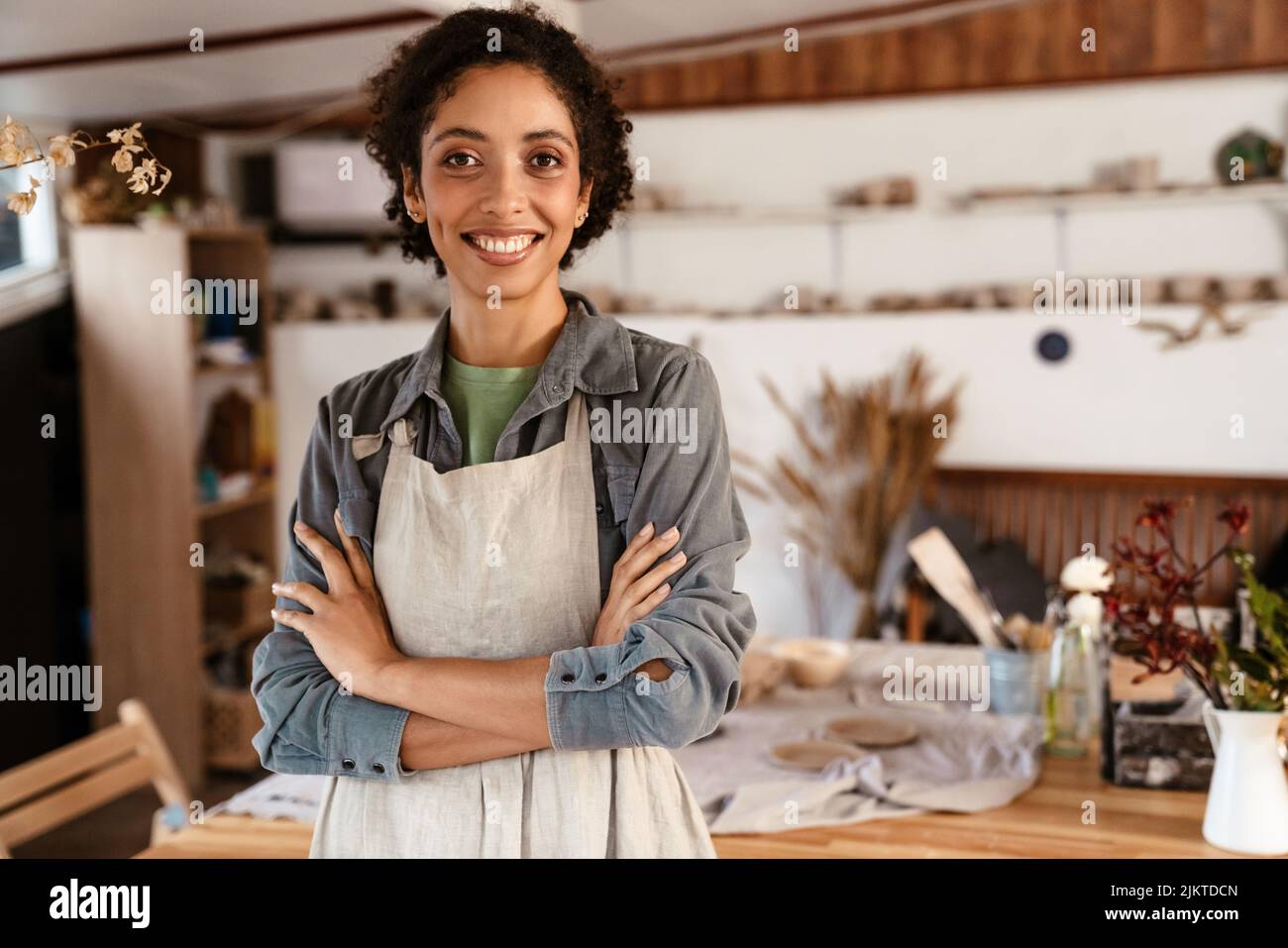 Young black ceramist woman wearing apron smiling while working in her ...