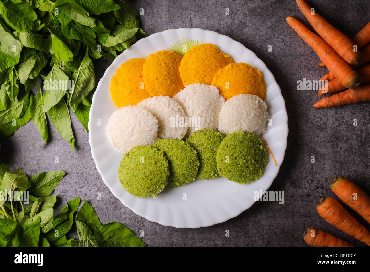 A top view of colorful Idli steamed round-shaped flatbreads on a plate ...