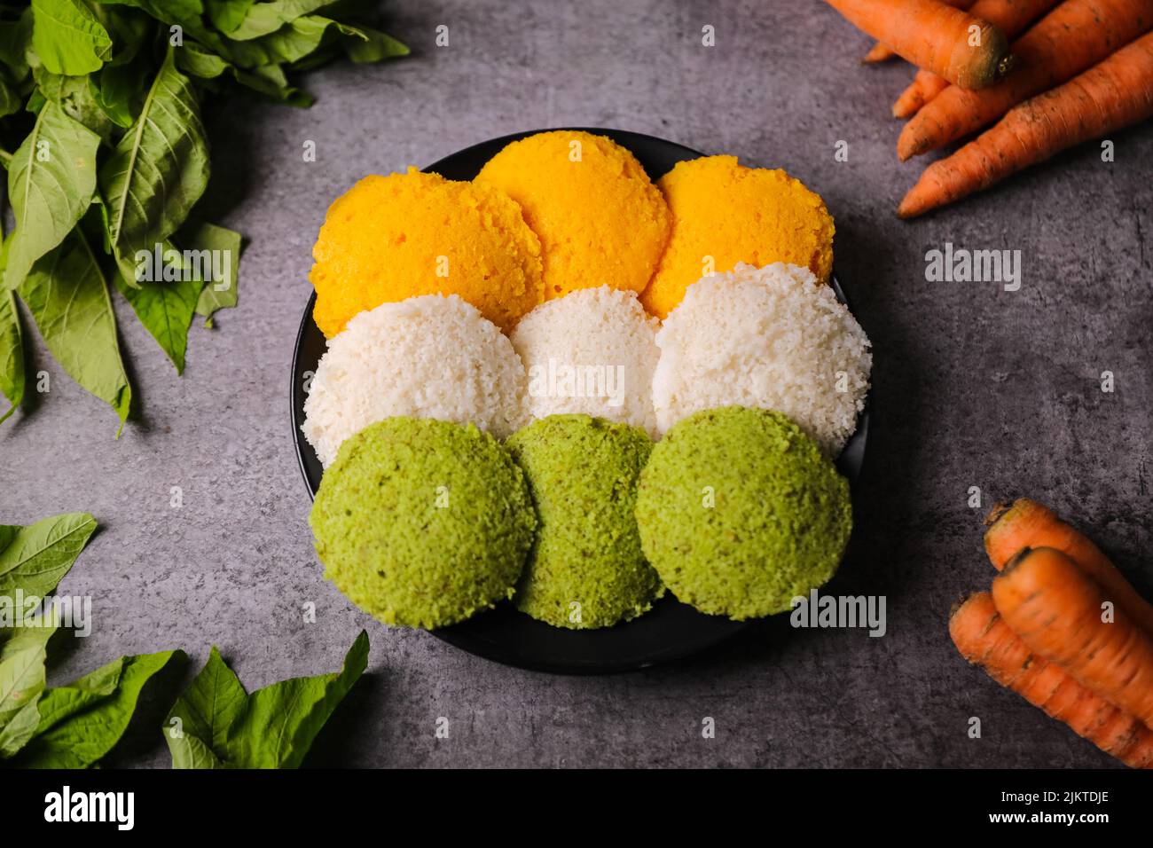 A top view of colorful Idli steamed round-shaped flatbreads on a plate ...