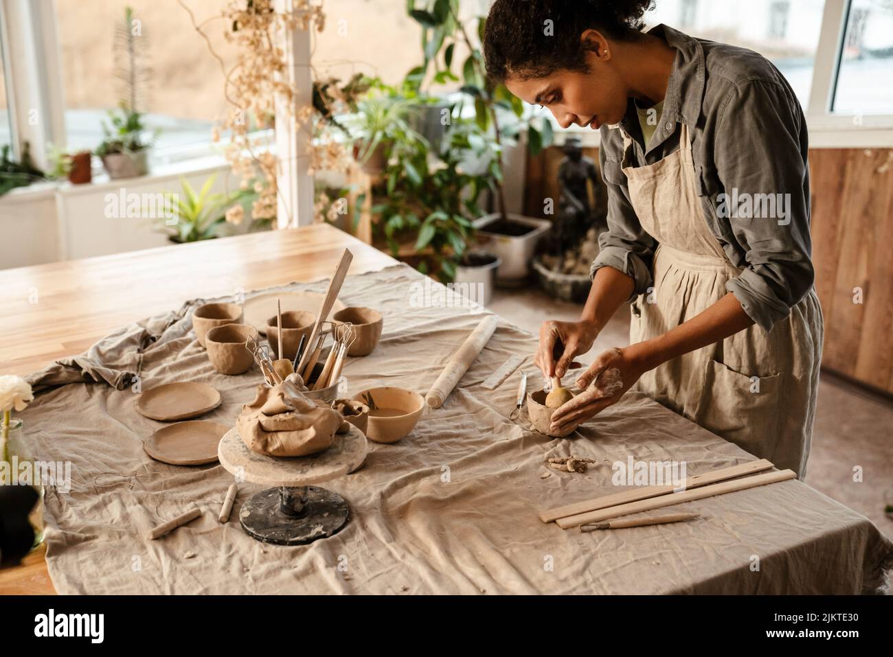 Young black ceramist woman wearing apron sculpting in clay at her workshop Stock Photo