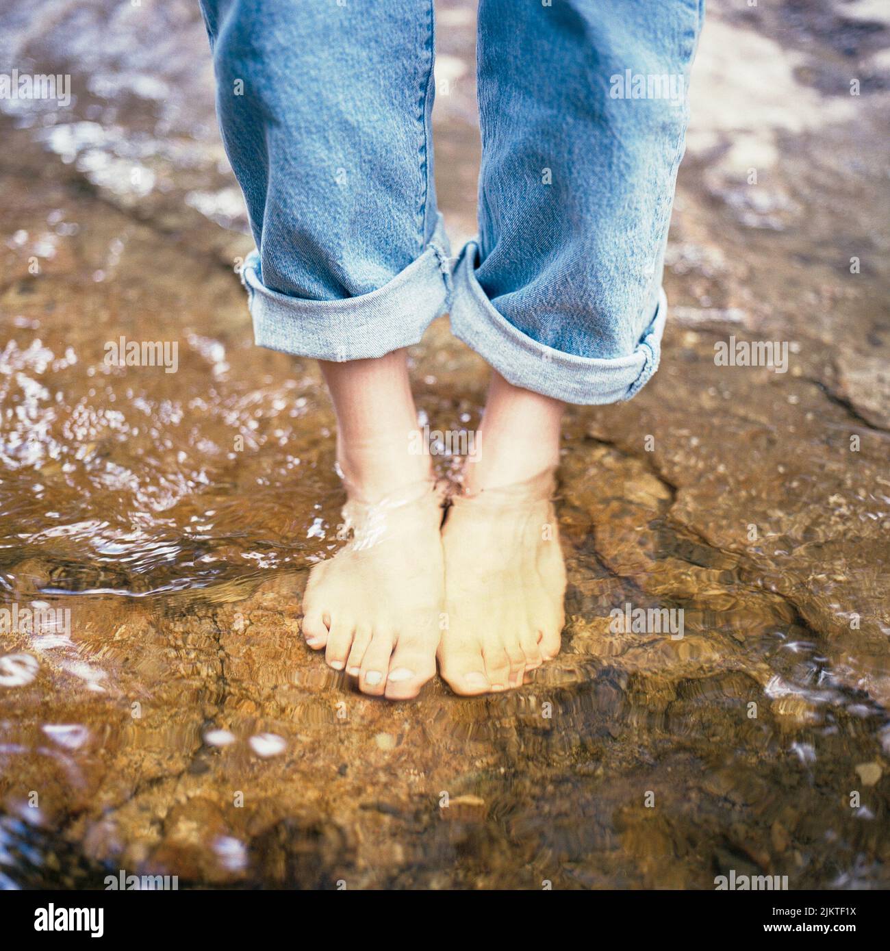 The human feet on the rocks in the water Stock Photo