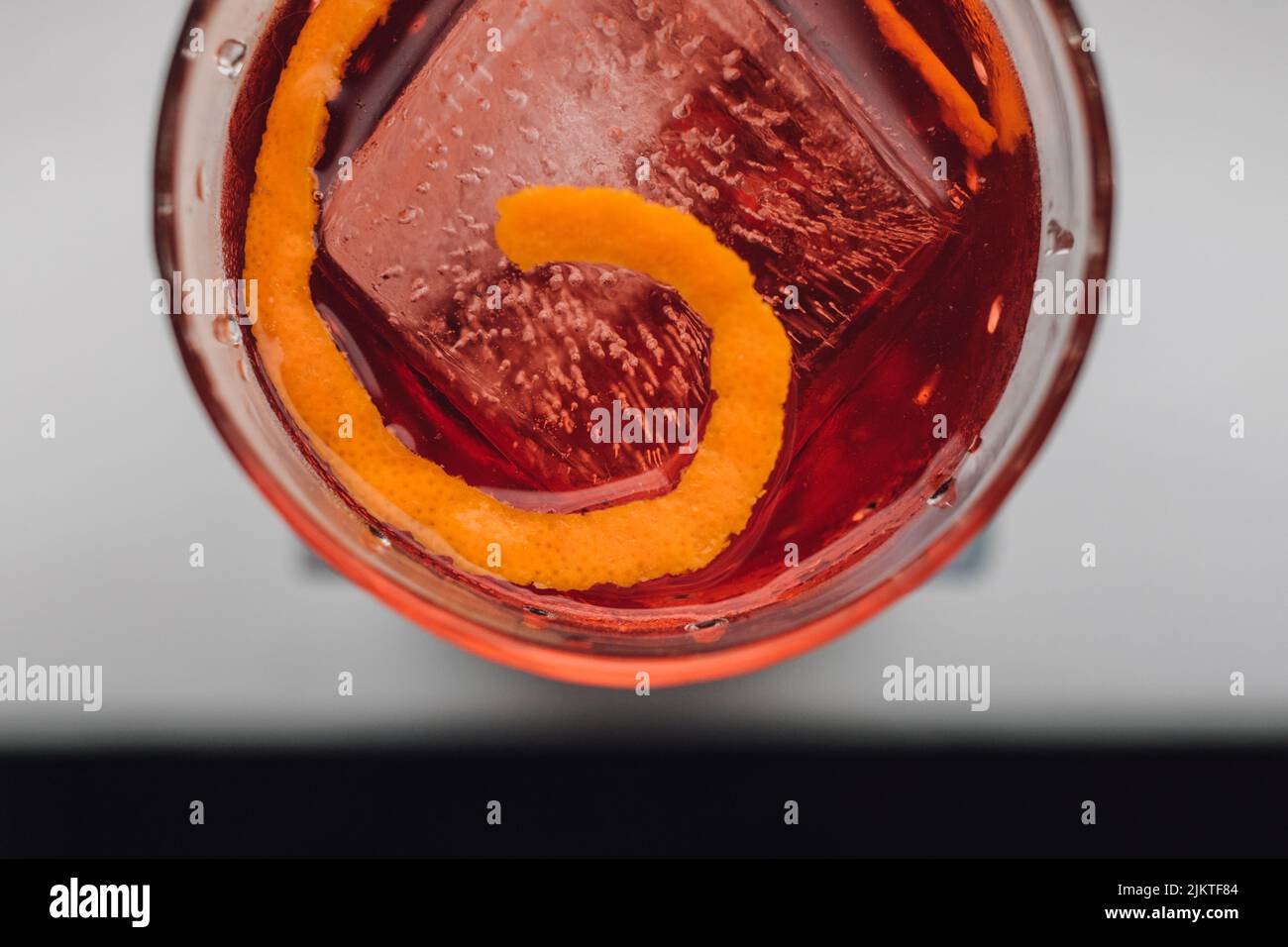 putting the G in Negroni, a cocktail with Campari, Gin, vermouth on ice with orange twist garnish Stock Photo