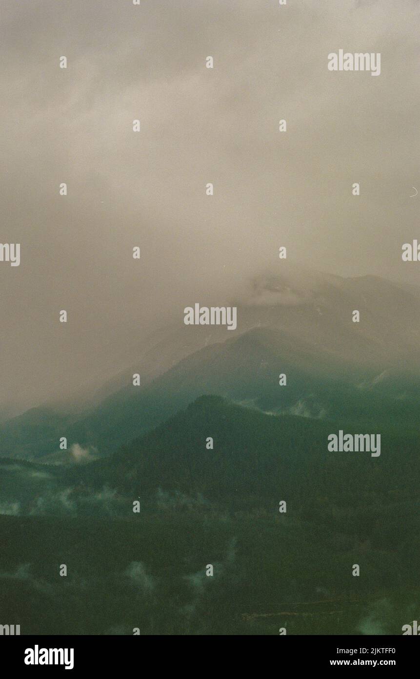 A vertical landscape with rocky mountains covered by mist Stock Photo