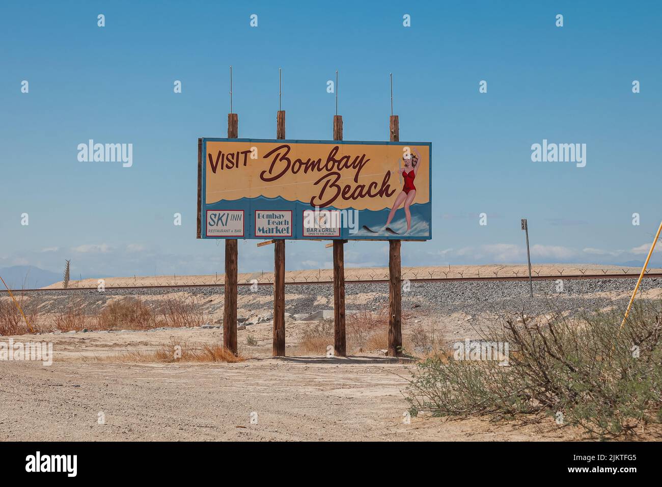 A retro wooden sign on Highway 111 tells drivers to Visit Bombay Beach in the desert. Stock Photo