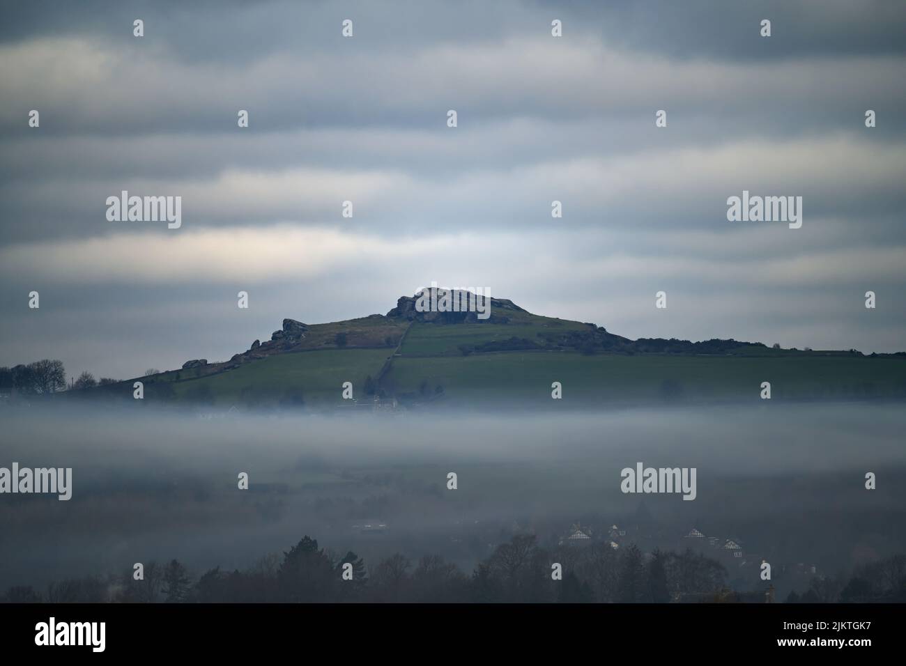 A panoramic shot of a mountain covered by clouds and mist layers Stock Photo