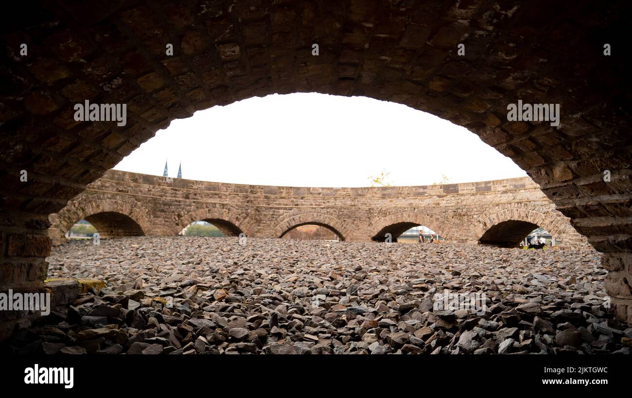 A view of a round building like square or a bridge with arched entrances to an area covered with gravel Stock Photo