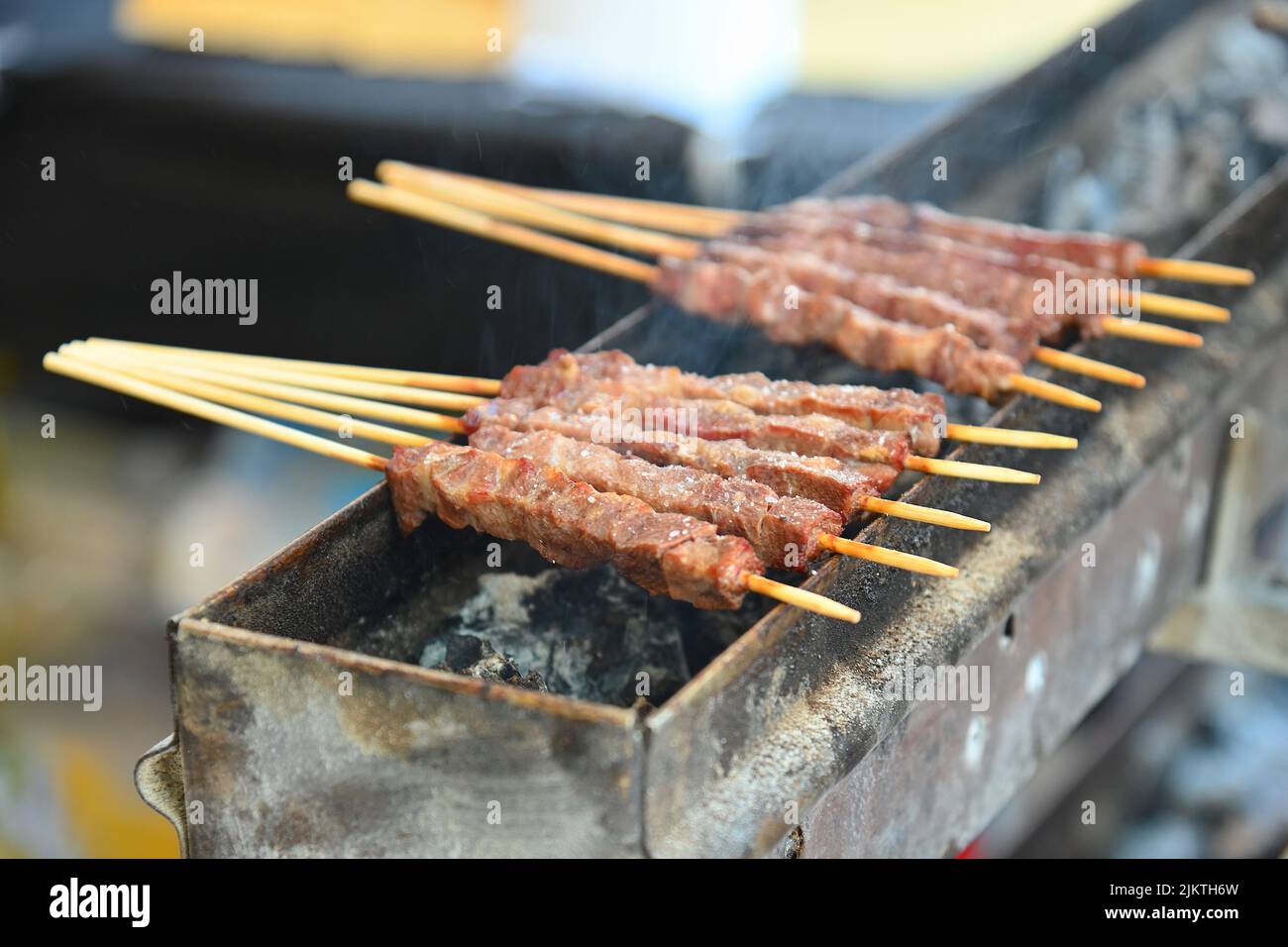 A closeup of typical skewers of lamb arrosticini cooking on a charcoal