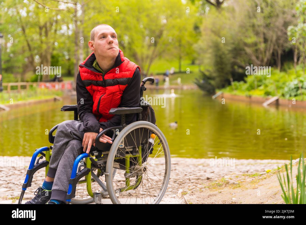 Portrait of a paralyzed young man in a public park in the city. Sitting