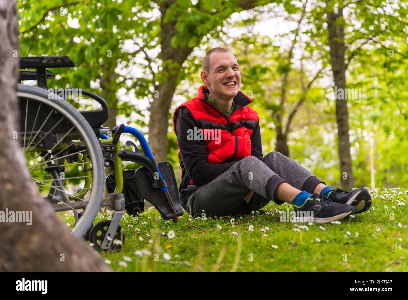 Portrait of a paralyzed young man sitting on the grass next to the