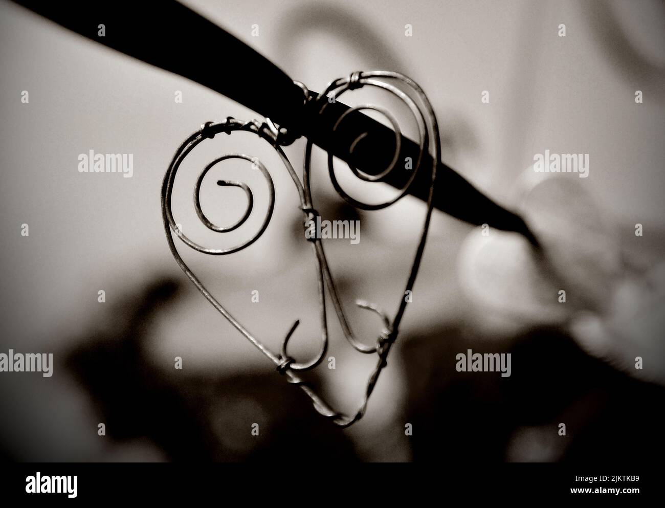 A grayscale view of a heart-shaped ornament hanging on a wire Stock Photo