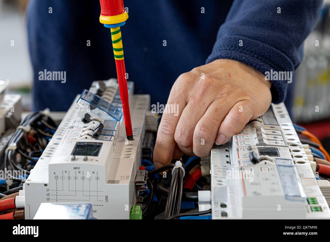 A closeup of the hands holding a screw while working on the electrical ...