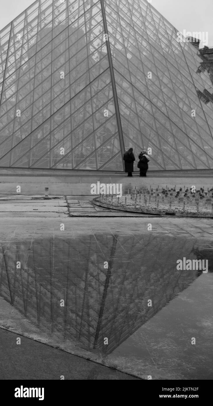 A grayscale view of the glass pyramid of Louvre on a rainy day, Paris, France Stock Photo