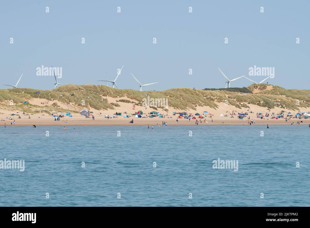 Little Cheyne Court Wind Farm - wind turbines visible behind sand dunes at Camber Sands, East Sussex, England, UK Stock Photo