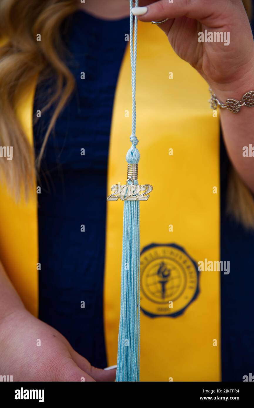 A vertical closeup shot of a light blue graduation tassel in the hands