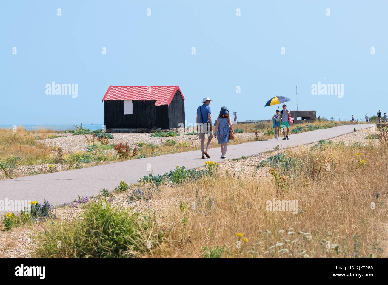 Rye Harbour Nature Reserve - tourists walking past the Red Roofed Hut in summer - Rye, East Sussex, England, UK Stock Photo