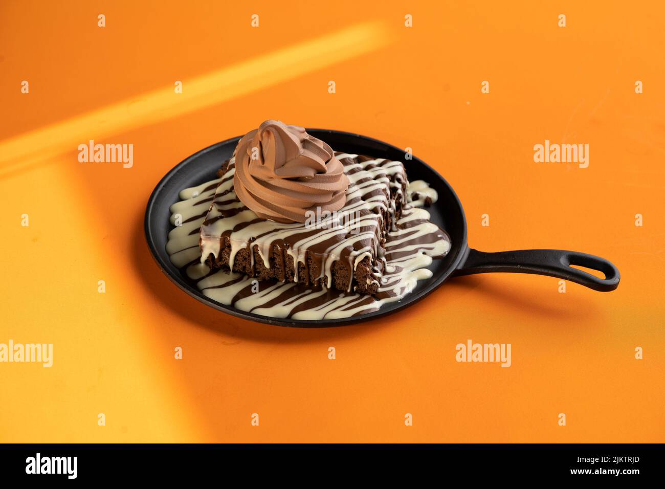 A brownie with melted dark and white chocolate and an ice cream on top ...