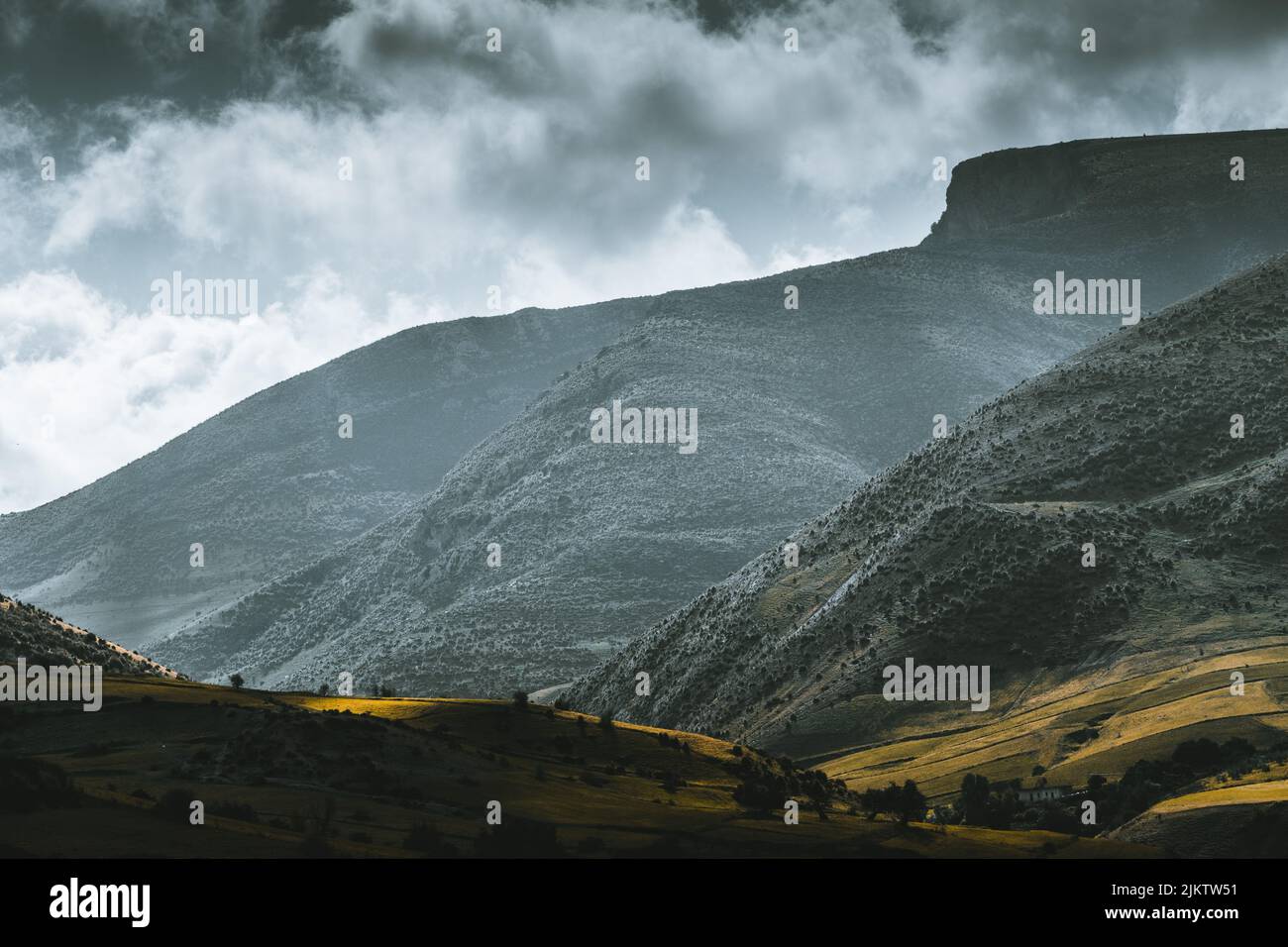 A peaceful mountainscape in the background of dramatic cloudy sky Stock Photo