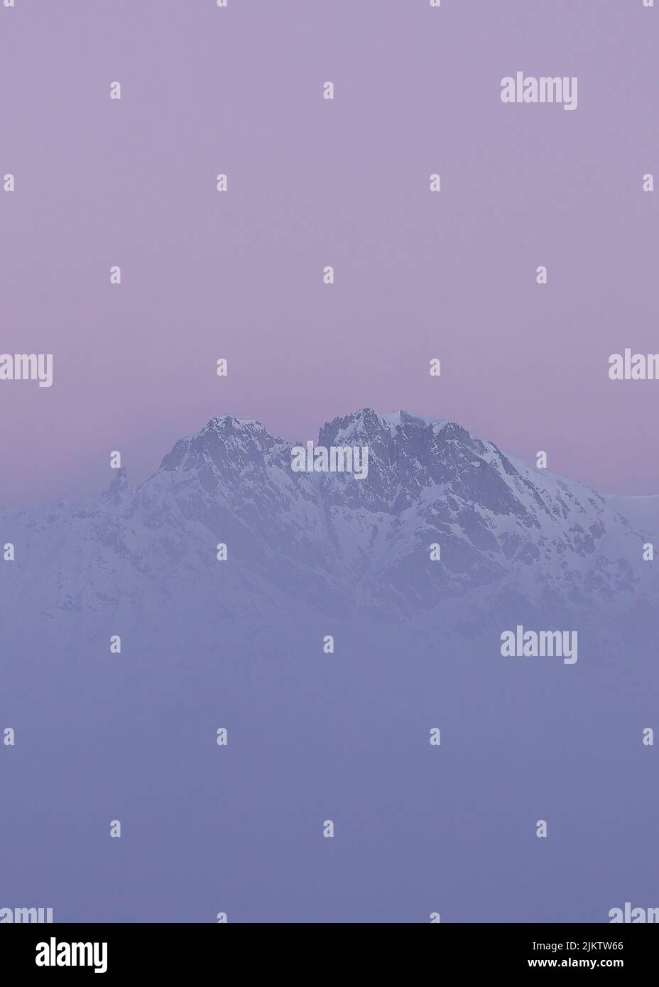 A scenic view of Nordkette mountain chain through the dense purple fog, Austria, Tirol, Innsbruck Stock Photo