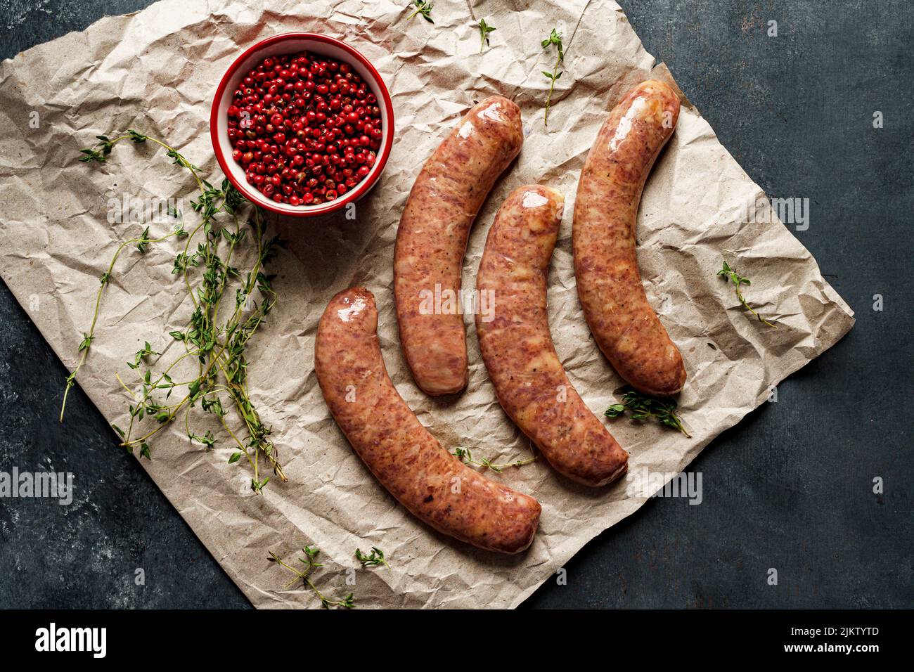 a top view of a fresh sausages with red pepper and green on a pergament paper Stock Photo