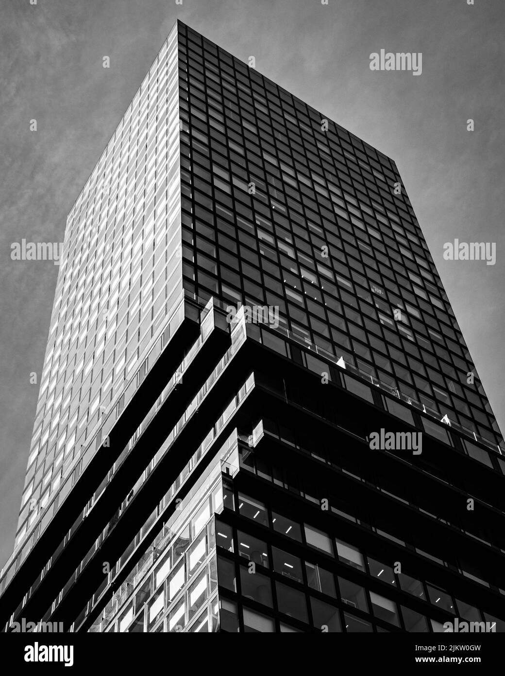 A vertical low angle grayscale view of a skyscraper with glass windows Stock Photo