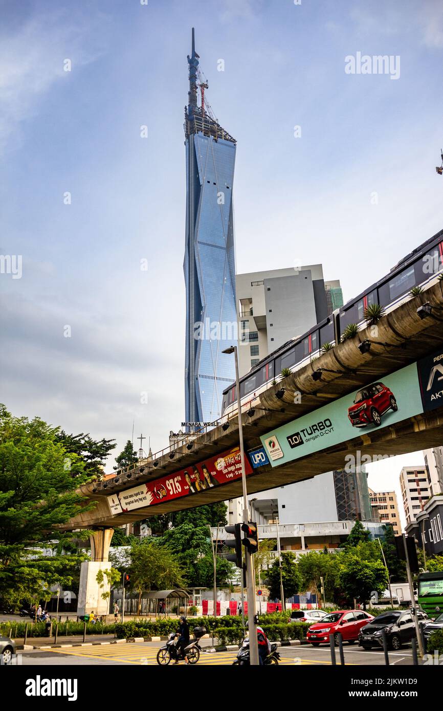 A vertical shot of the world's second-tallest building Warisan Merdeka Tower with the train running on the foreground Stock Photo