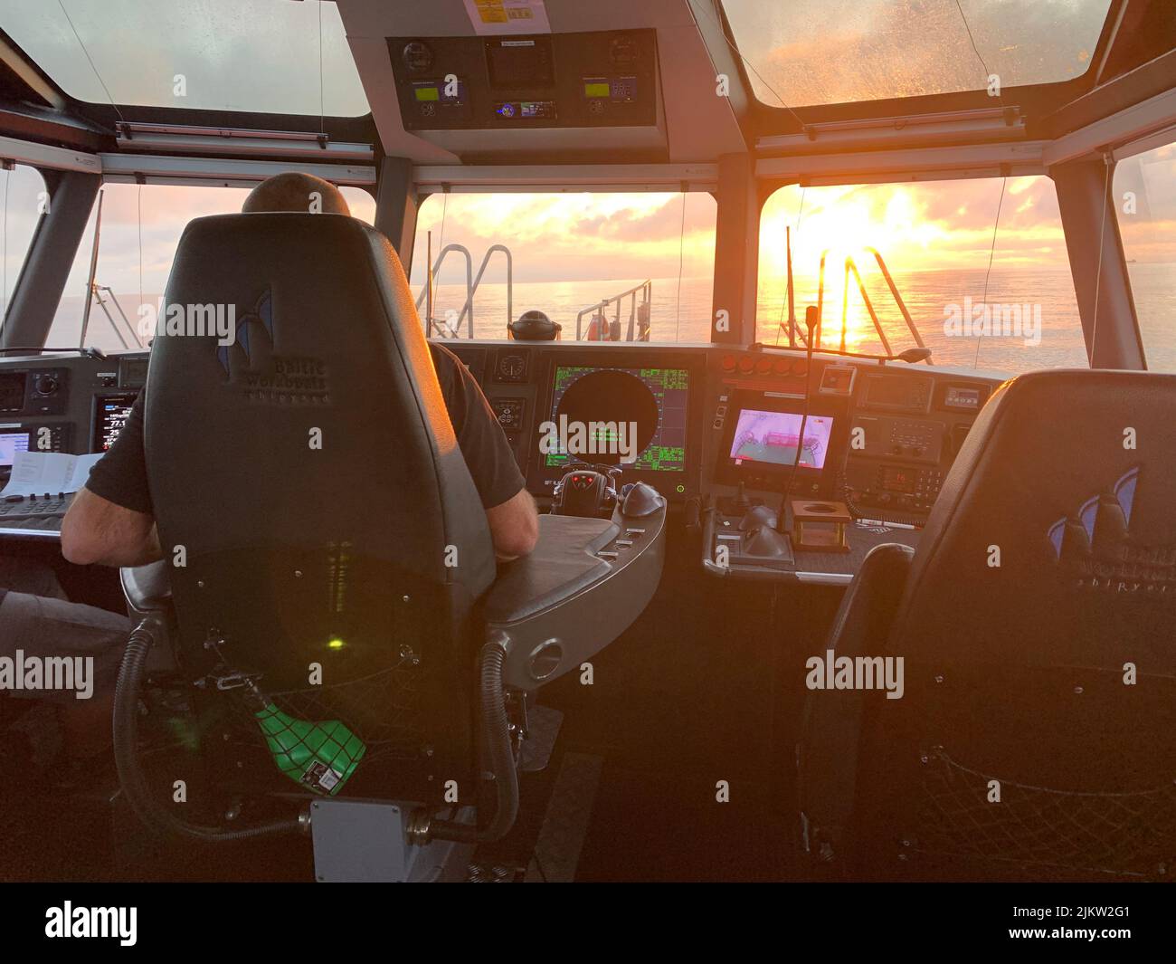 A back view of a man driving a pilot boat during the sunset Stock Photo