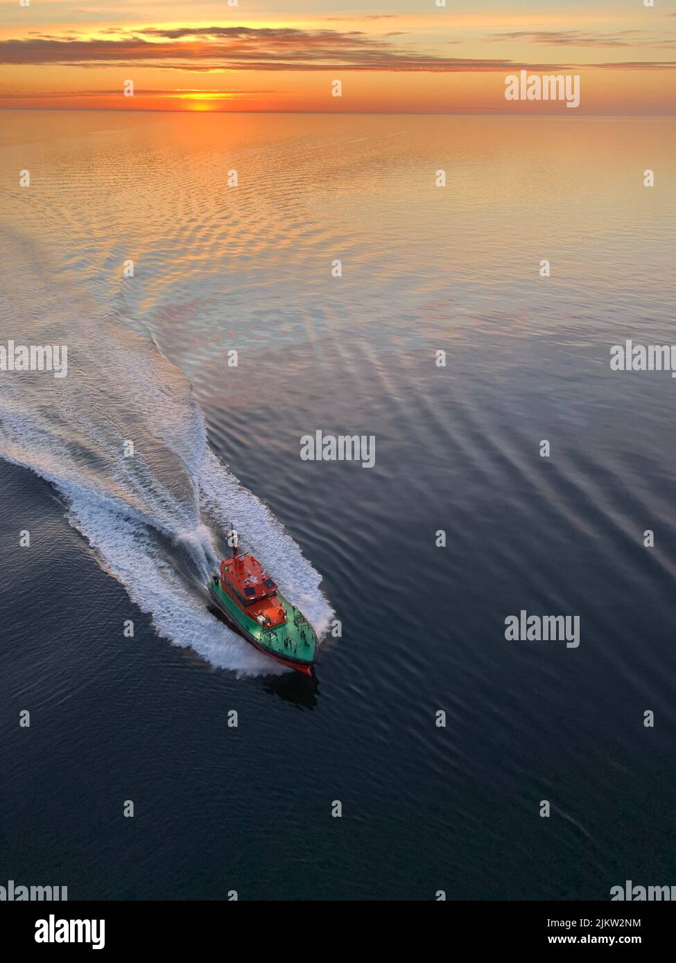 A vertical aerial view of a pilot boat approaching to a big vessel in