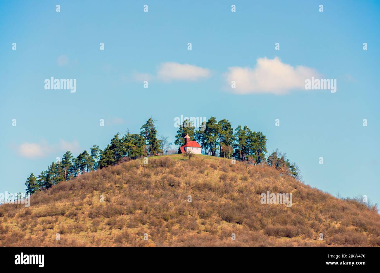 A scenic view of a small church on top of a hill in cloudy sky background Stock Photo