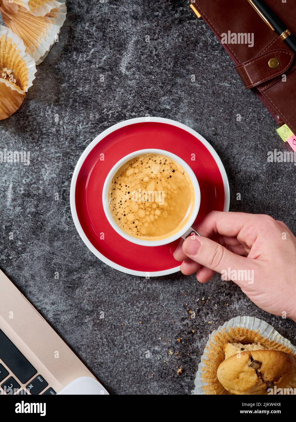 A vertical shot of a hand holding a cup of espresso in a saucer Stock Photo