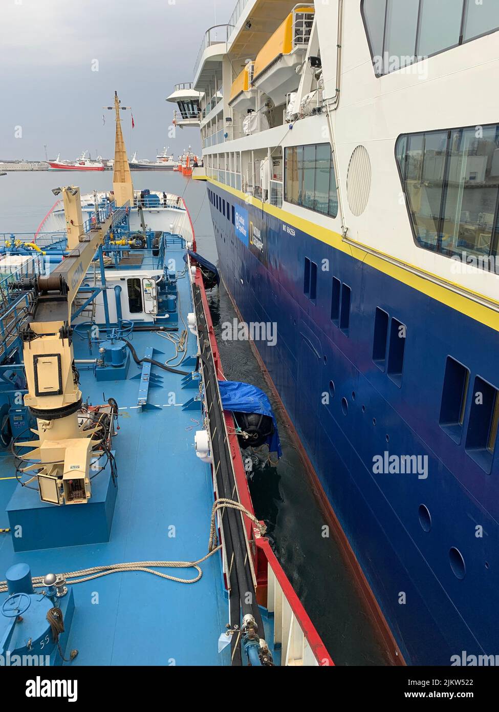 A vertical shot of a bunker vessel next to the big cruise ship for oil