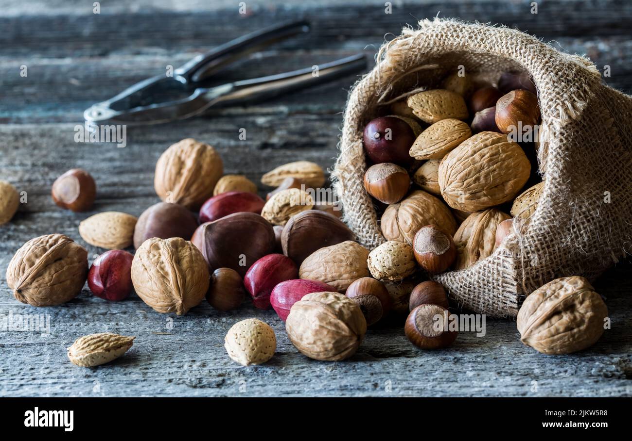 Whole nuts pouring out of a burlap sack with nut crackers in behind