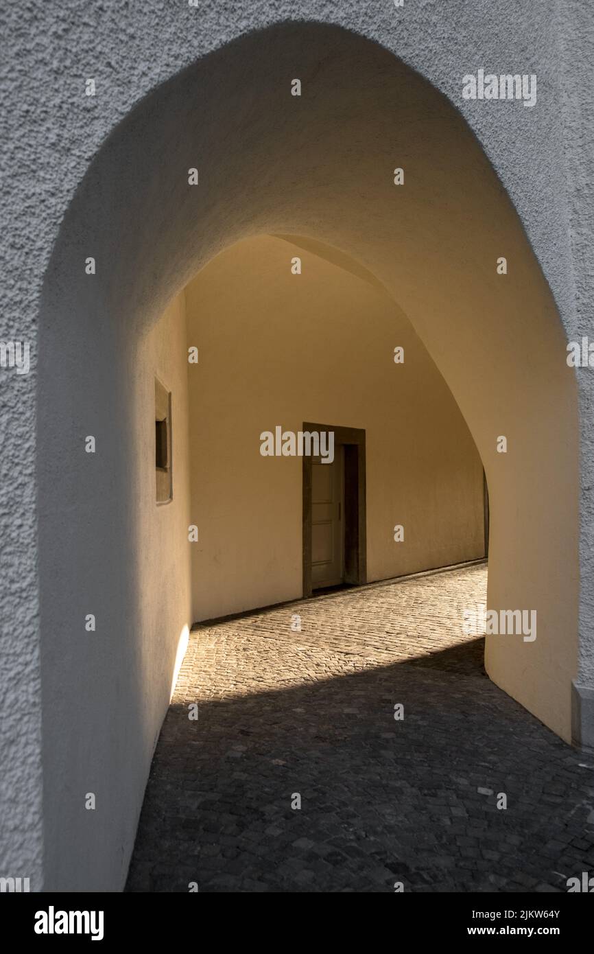 A vertical shot of a stone white arch with sunbeams at the end in St. Gallen, Switzerland Stock Photo