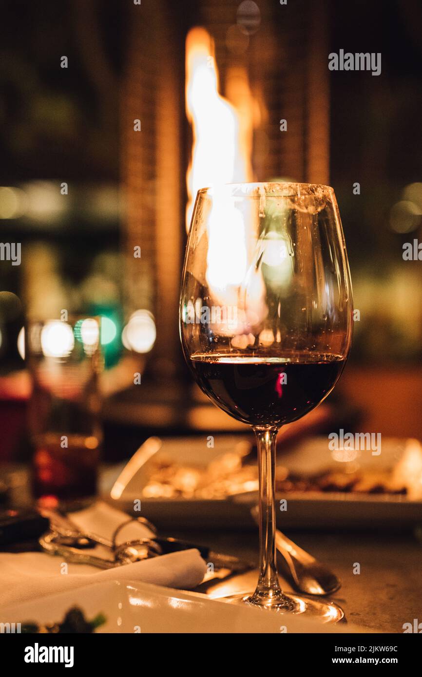a glass of Red wine on outdoor restaurant table with heater at night Stock Photo