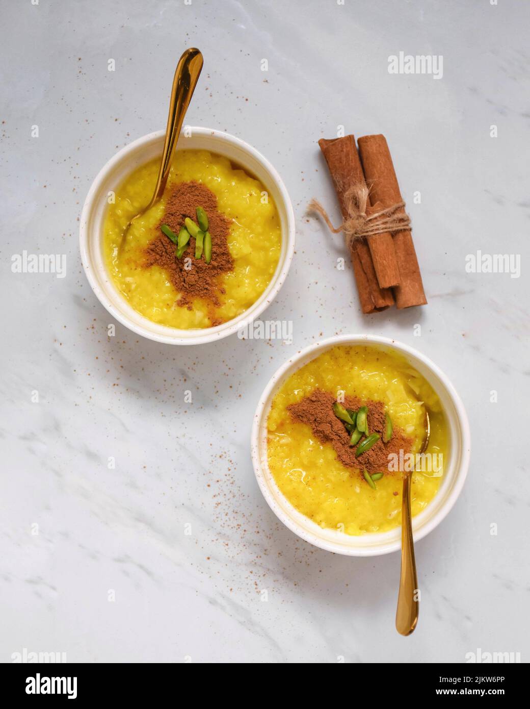 Two portions of saffron rice pudding served with cinnamon. Stock Photo