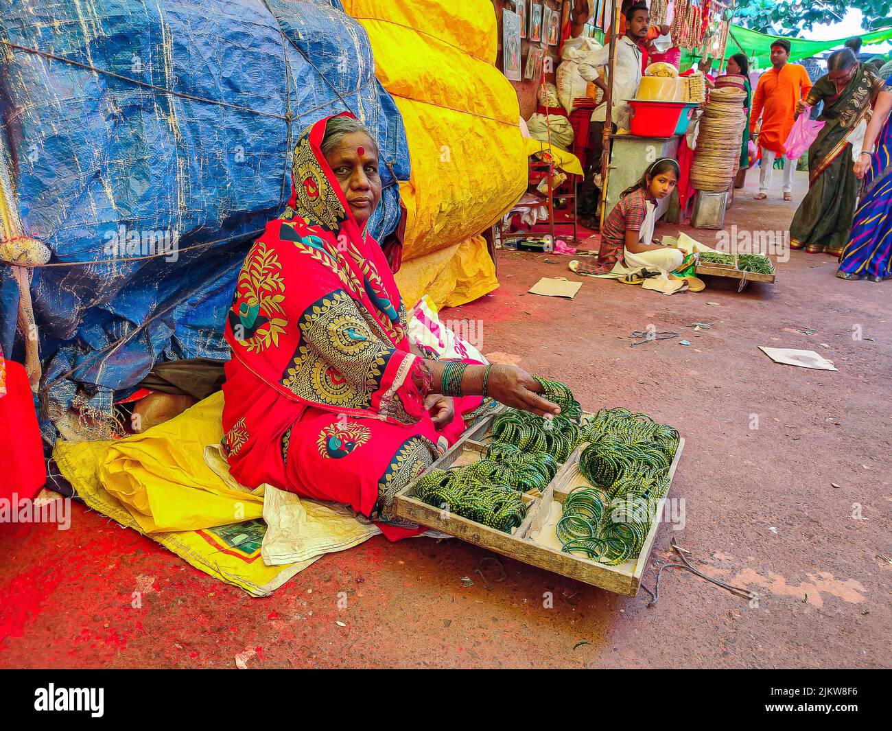 Tuljapur, India- December 19th 2019; Stock photo of 50 to 60 age group Indian women wearing red color saree, selling green color traditional glass ban Stock Photo