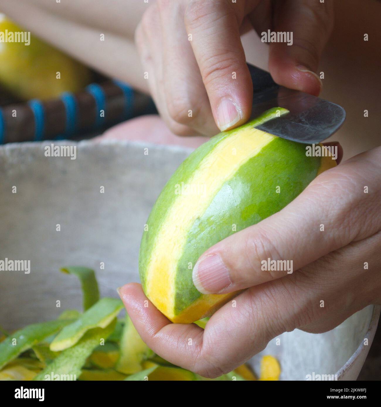 Woman hand using a knife to peel ripe mango. The local fruits are sweet